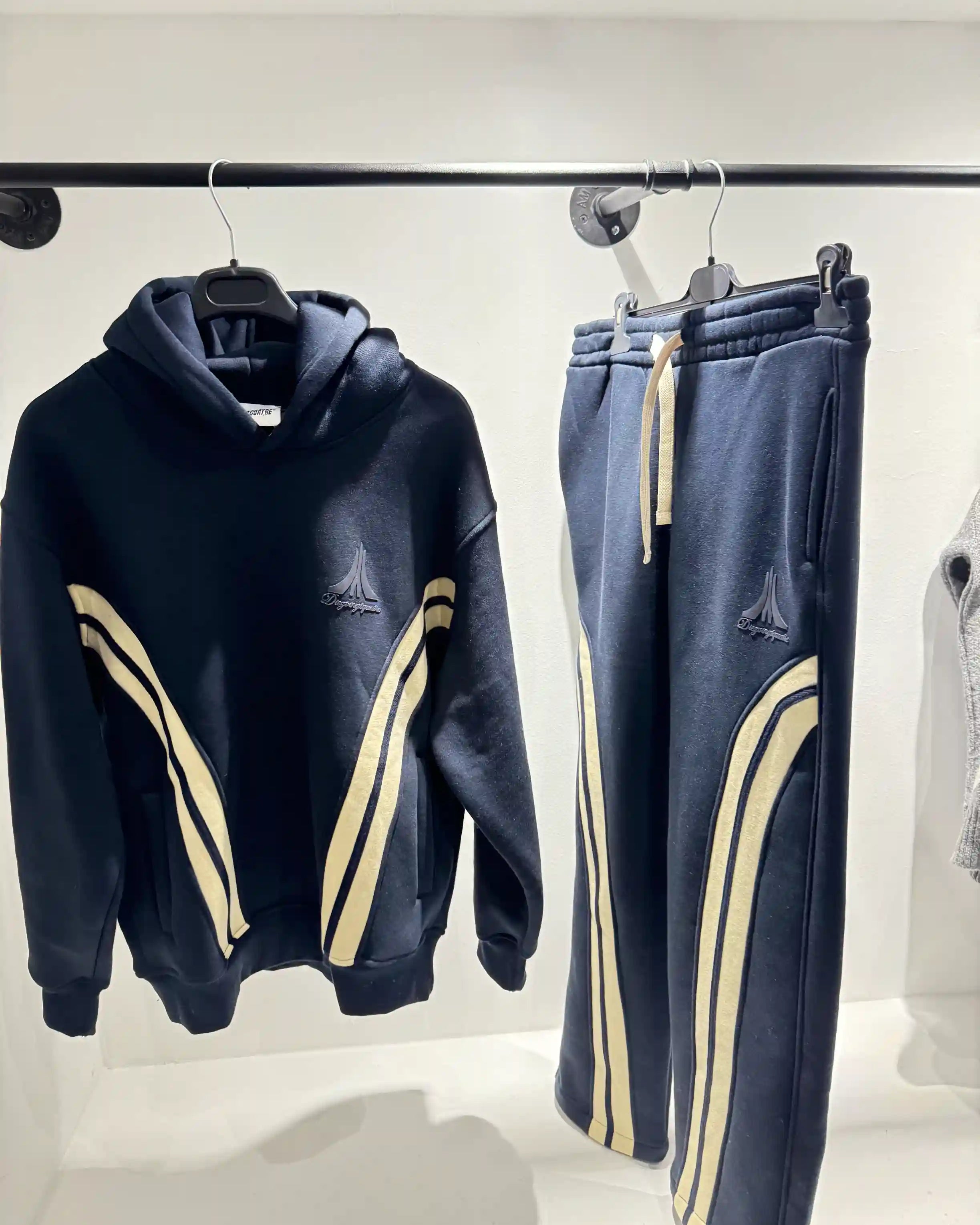 Présentation de l'ensemble bleu foncé et beige sur cintre, illustrant le tombé du vêtement et le design des bandes.