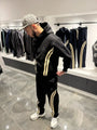 Ensemble streetwear noir avec veste zippée et jogging, présentant de larges bandes beiges verticales sur les bras et les jambes.