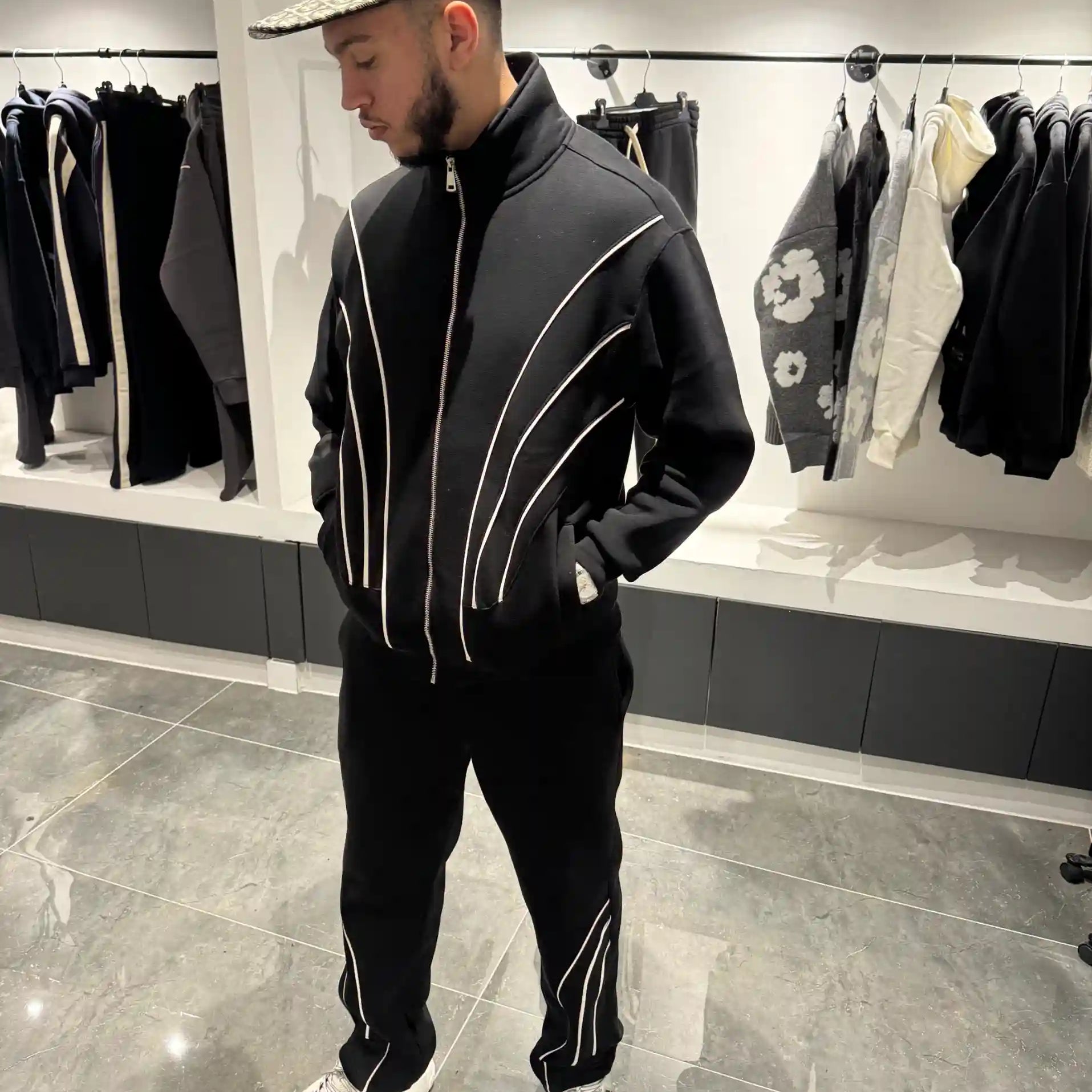 Silhouette complète présentant l'ensemble noir et l'effet visuel des fines lignes blanches sur le gilet et le pantalon.