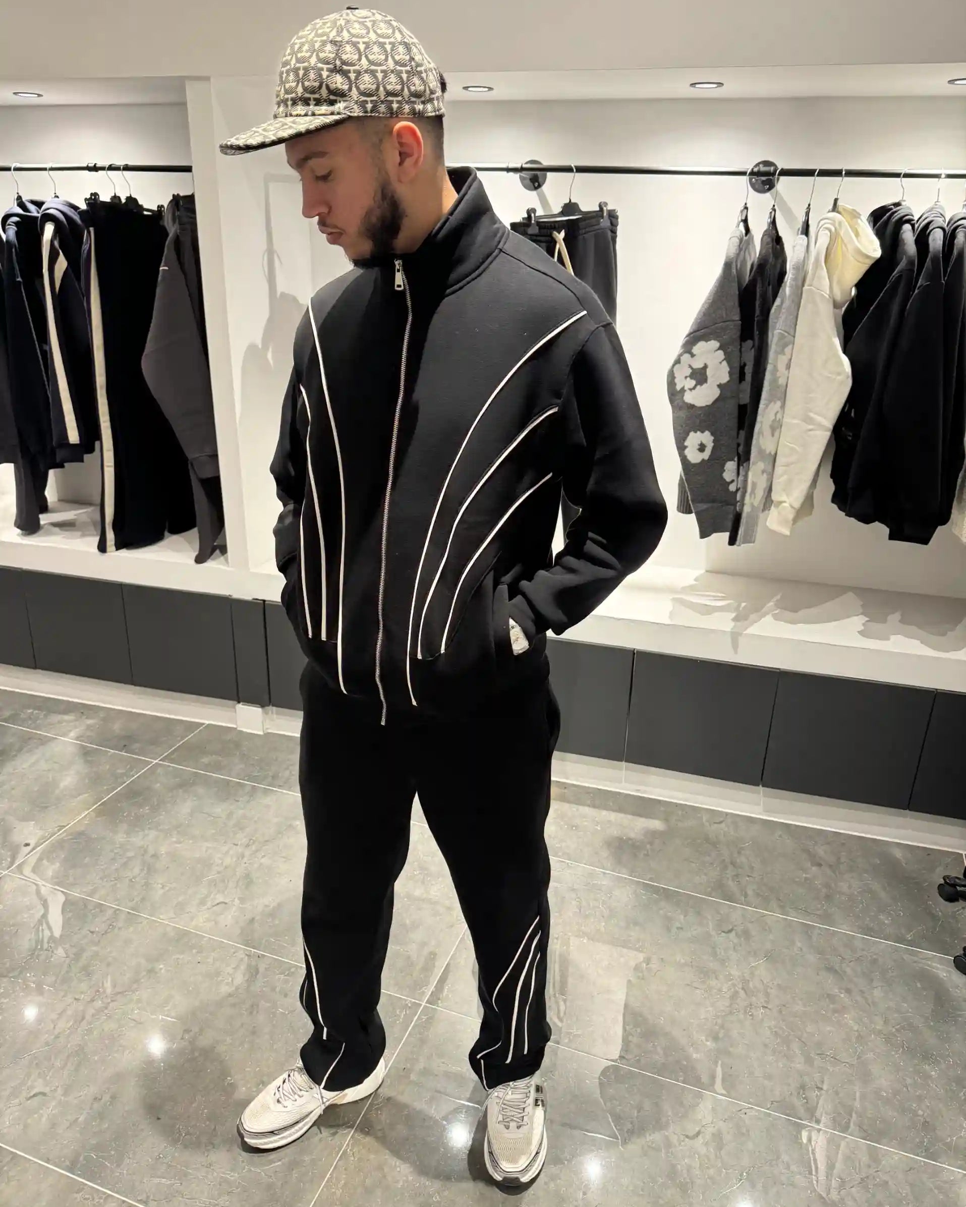 Silhouette complète présentant l'ensemble noir et l'effet visuel des fines lignes blanches sur le gilet et le pantalon.