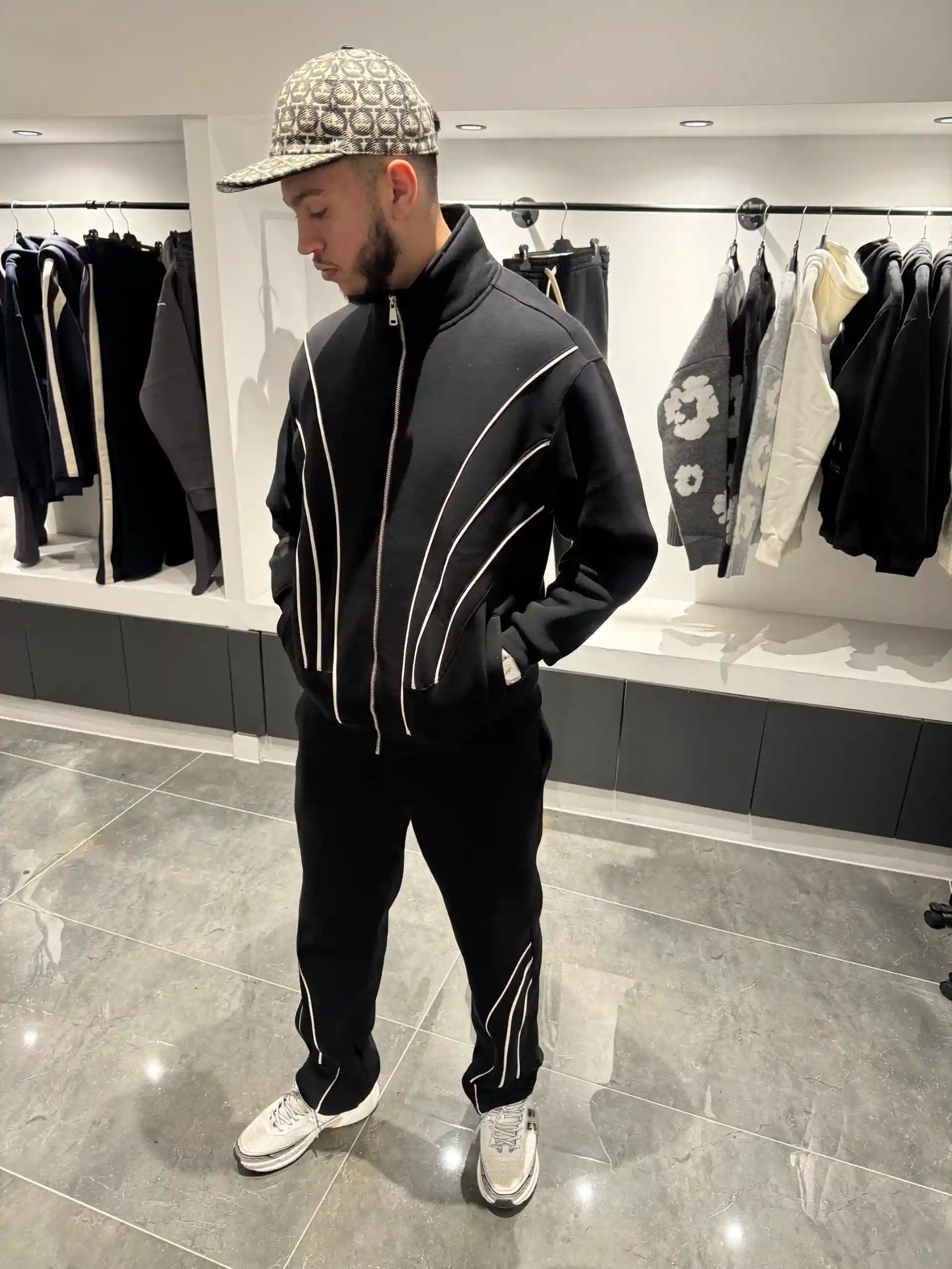 Silhouette complète présentant l'ensemble noir et l'effet visuel des fines lignes blanches sur le gilet et le pantalon.