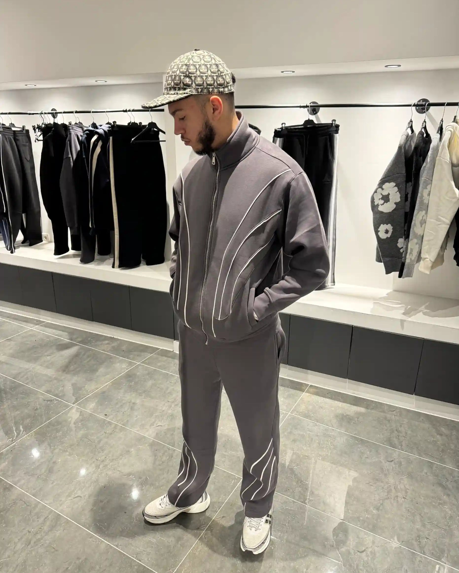 Silhouette complète présentant l'ensemble gris et l'effet graphique des fines lignes blanches sur le gilet et le pantalon.