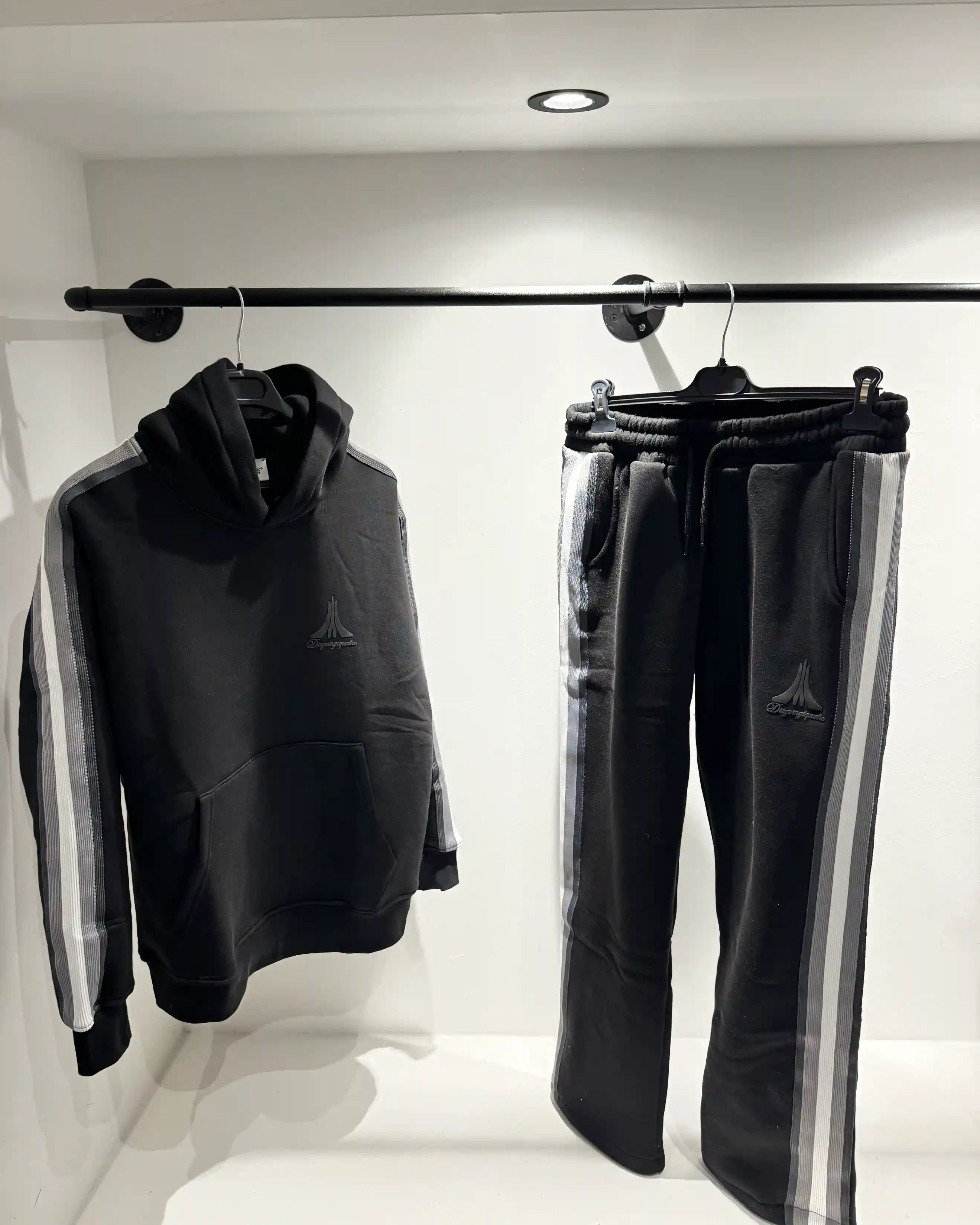 Présentation de l'ensemble noir sur cintre, illustrant la qualité des finitions et le design des bandes latérales.