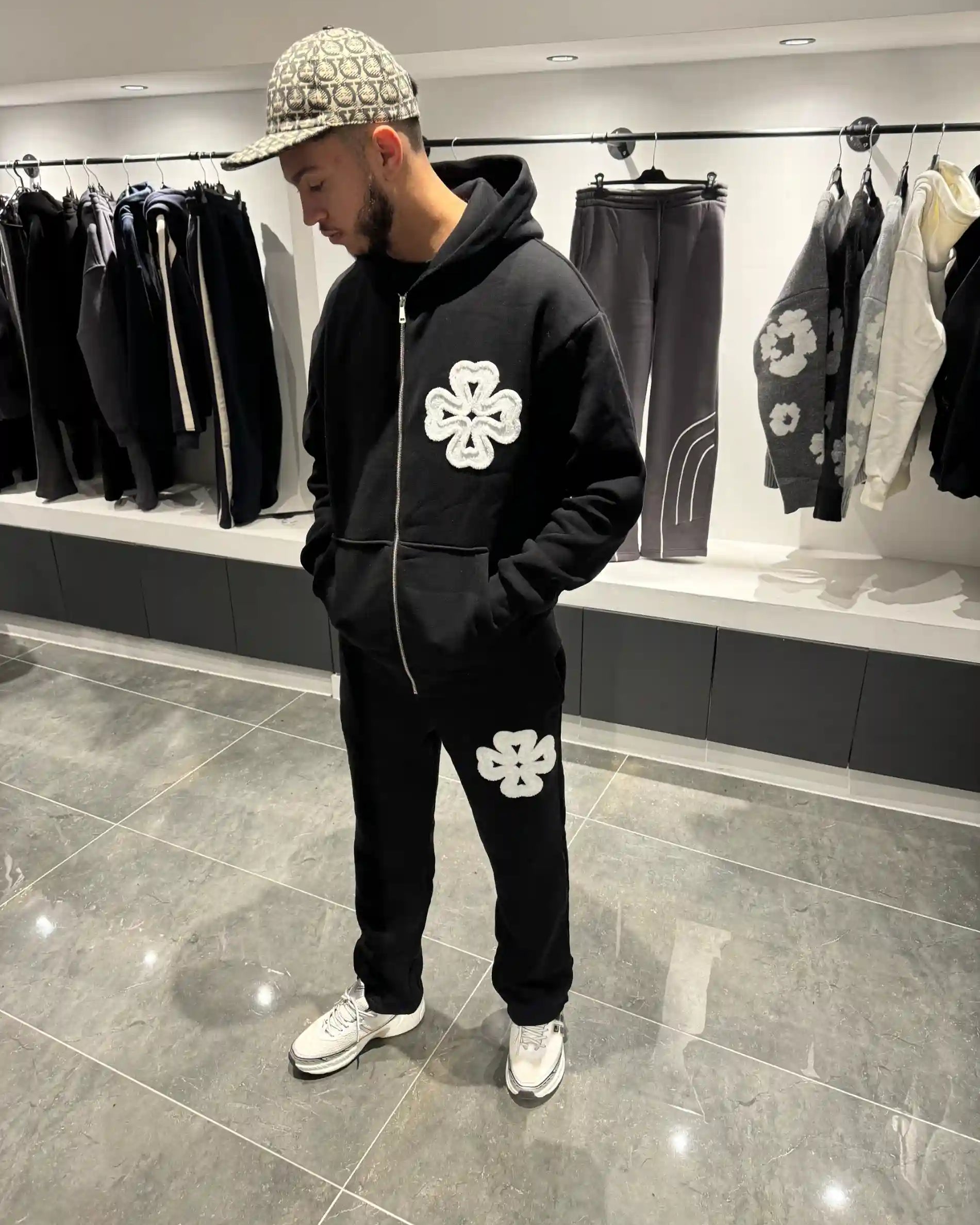 Silhouette complète présentant l'ensemble noir et les motifs trèfles blancs sur la poitrine et la jambe.