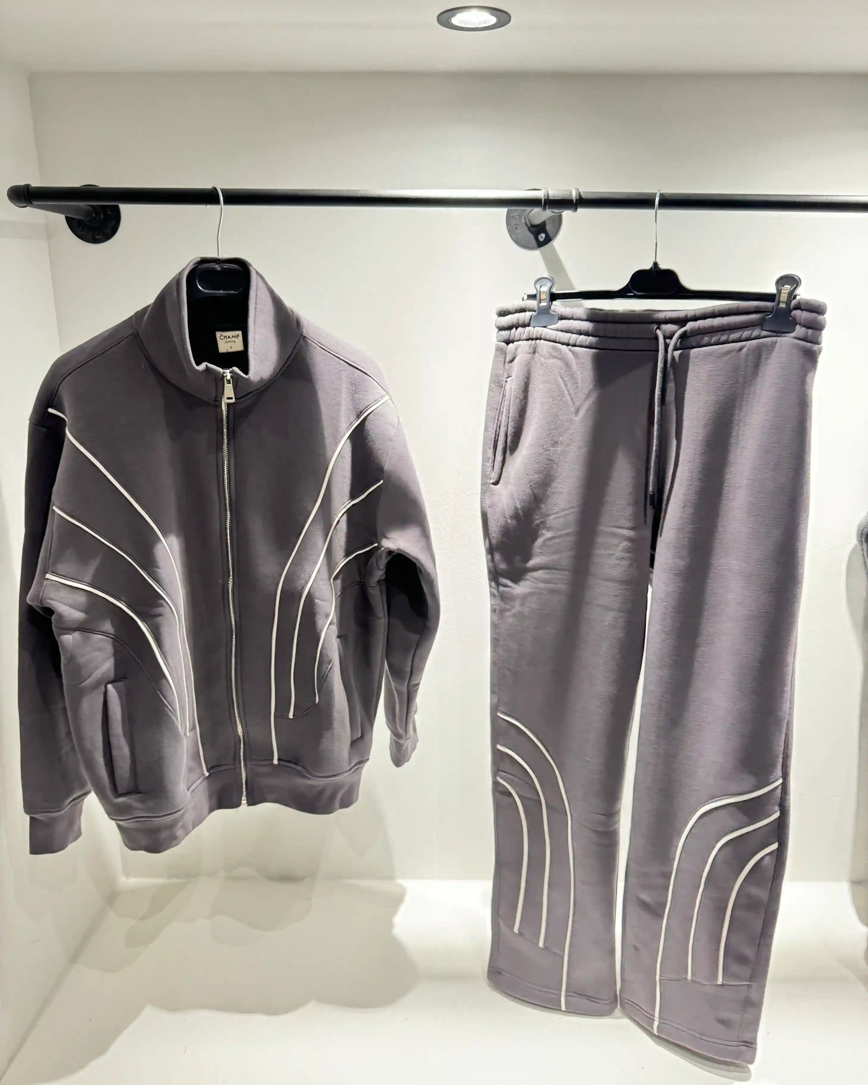 Présentation de l'ensemble gris à lignes blanches sur cintre, illustrant le tombé fluide du vêtement et la netteté de ses finitions.