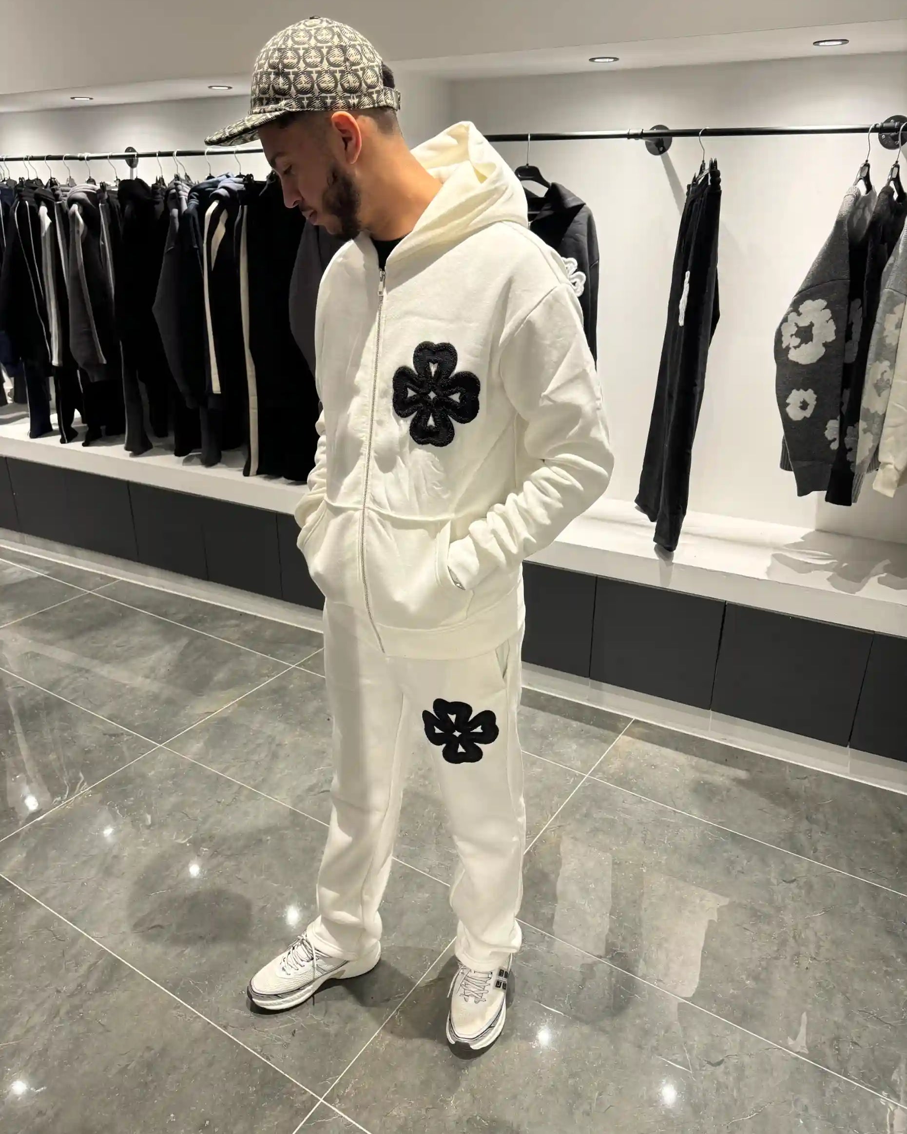 Silhouette complète présentant l'ensemble blanc et les motifs trèfles noirs sur la poitrine et la jambe.