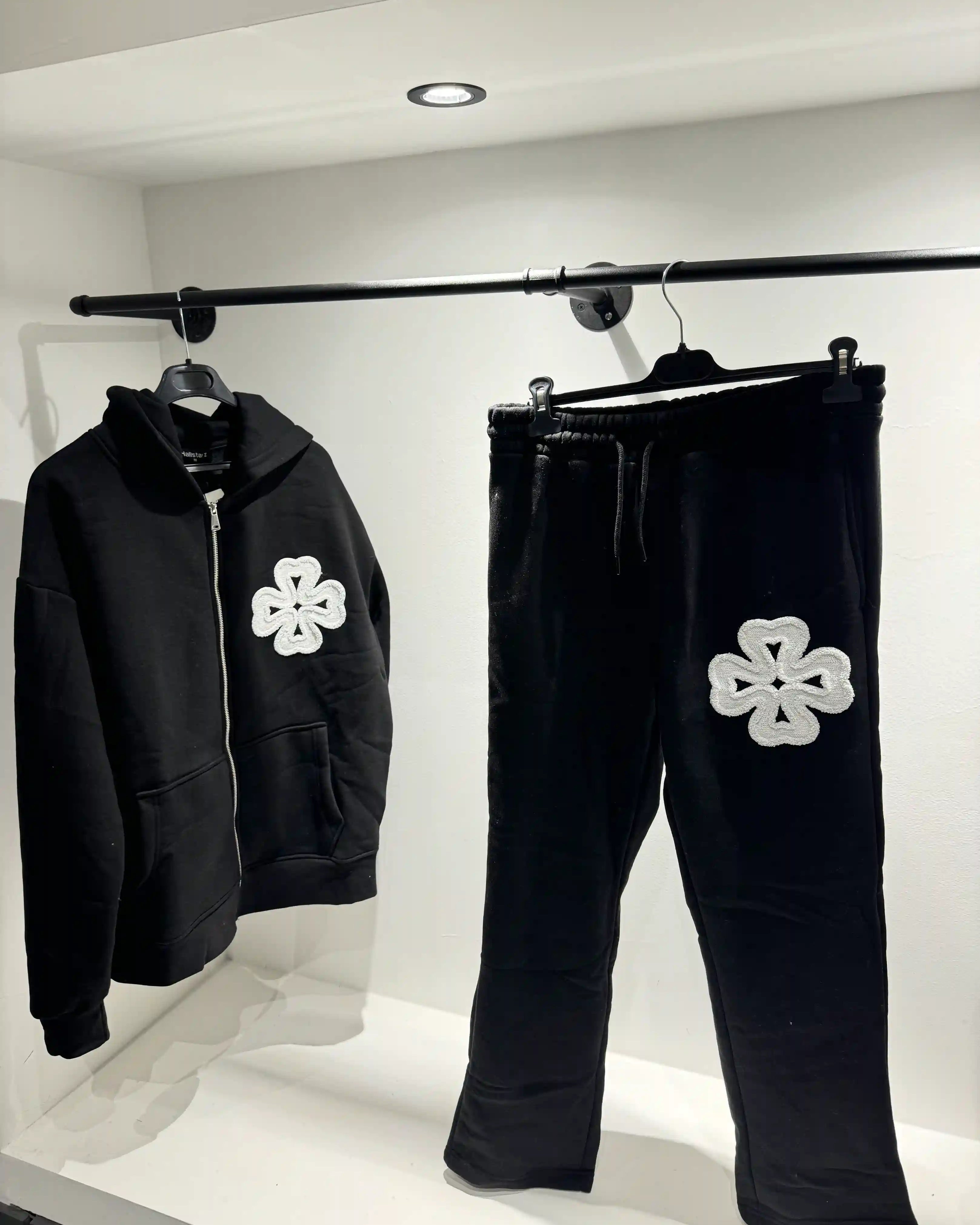 Présentation de l'ensemble noir sur cintre, illustrant le tombé du gilet et la visibilité des détails trèfles.