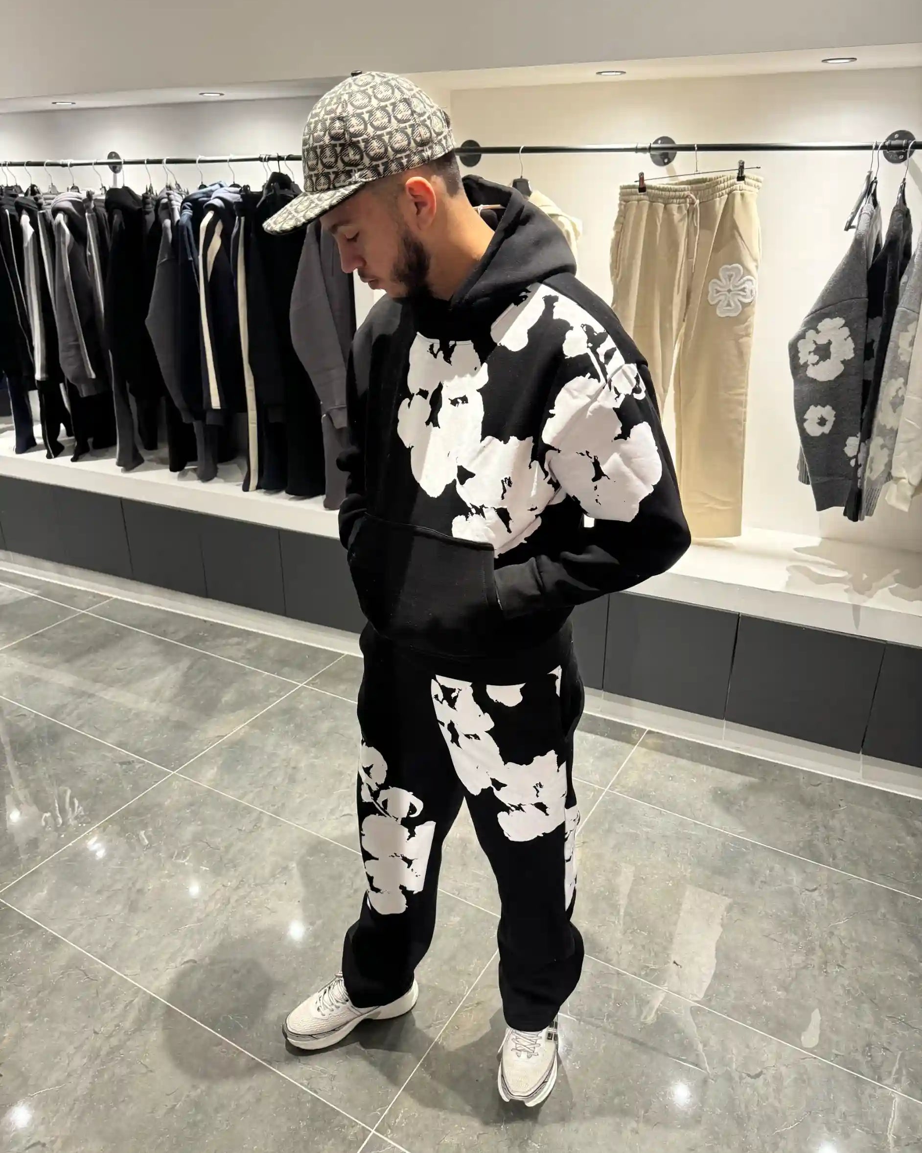 Silhouette complète présentant l'ensemble noir et l'imprimé floral blanc imposant sur le torse et la jambe.