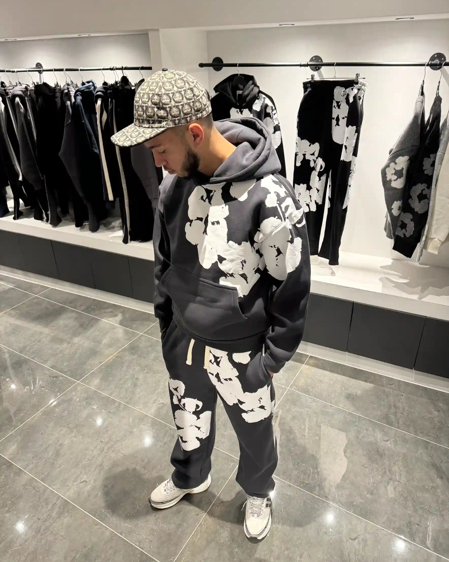 Silhouette complète en ensemble gris foncé avec les fleurs blanches imposantes bien visibles.