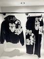 Présentation de l'ensemble noir sur cintre, illustrant le tombé du hoodie et la disposition imposante du print.