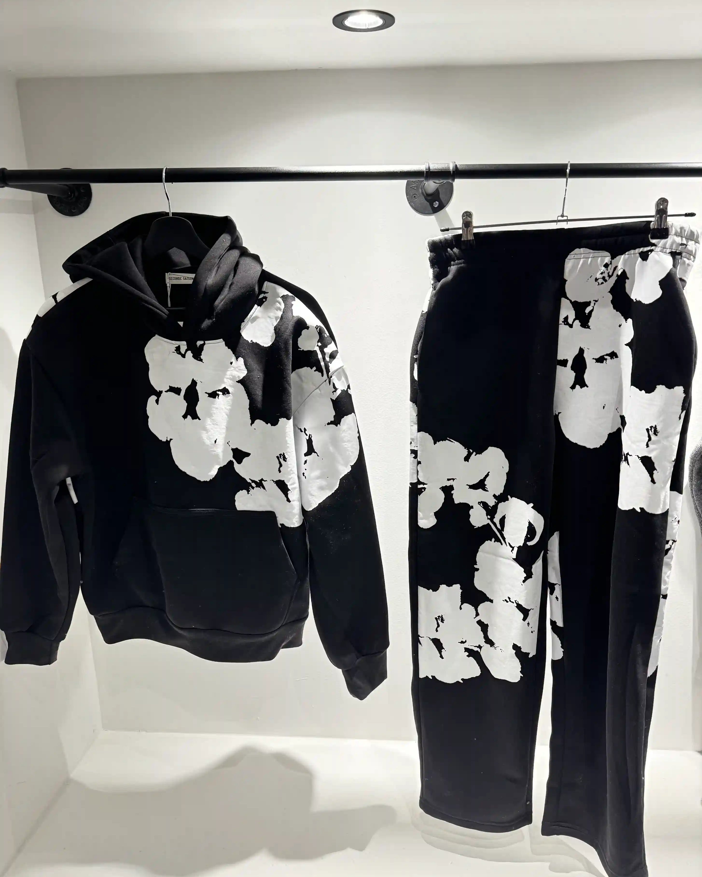 Présentation de l'ensemble noir sur cintre, illustrant le tombé du hoodie et la disposition imposante du print.