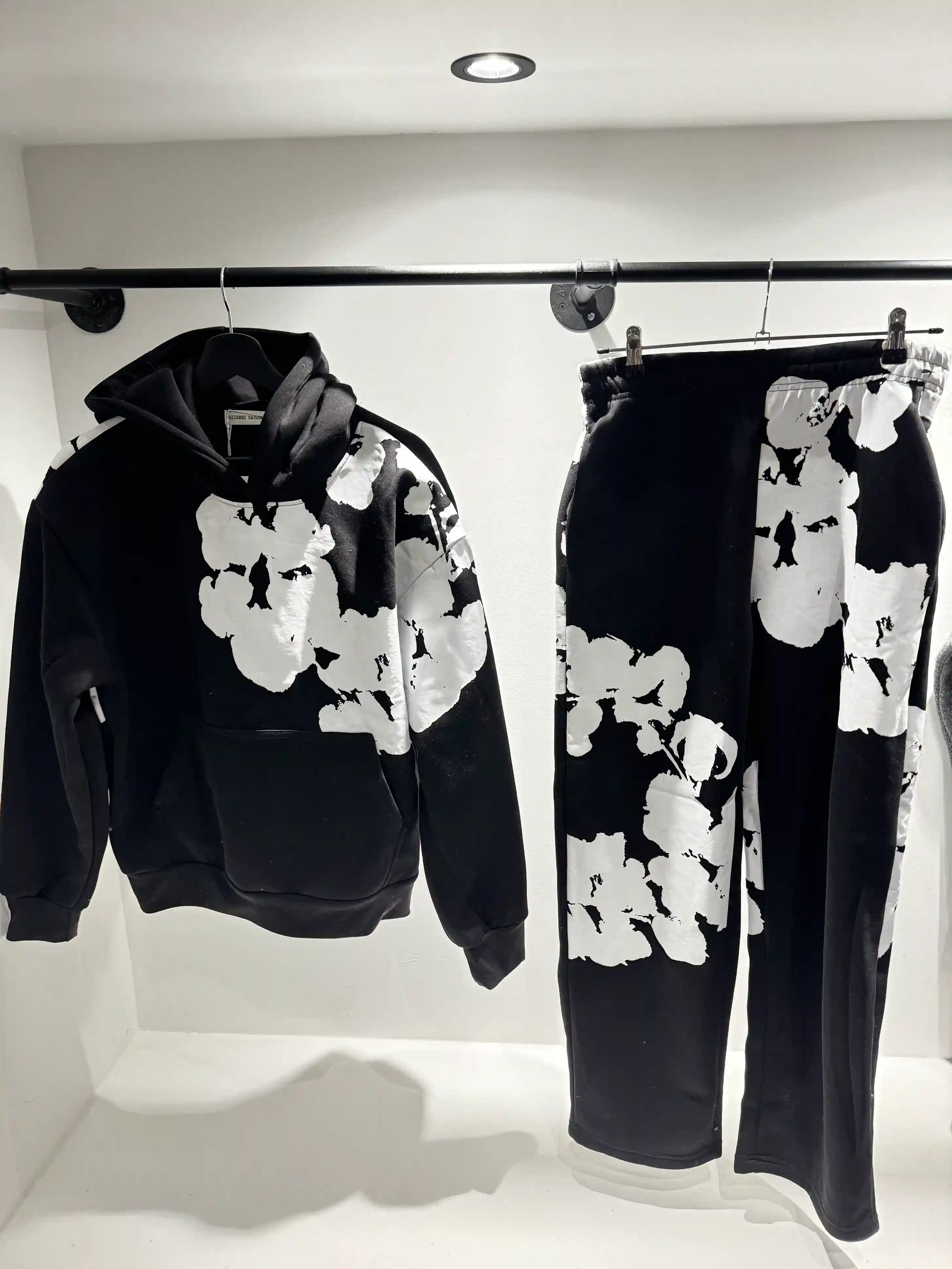 Présentation de l'ensemble noir sur cintre, illustrant le tombé du hoodie et la disposition imposante du print.