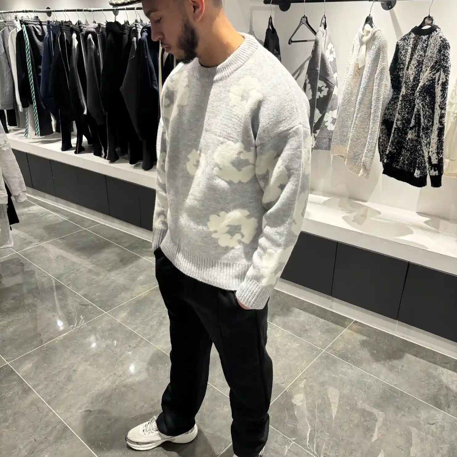Silhouette complète lumineuse présentant le pull gris et ses fleurs blanches tissées.
