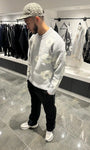 Silhouette complète lumineuse présentant le pull gris et ses fleurs blanches tissées.