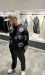 Silhouette complète présentant le pull noir et ses motifs floraux gris répartis sur l'ensemble de la maille.