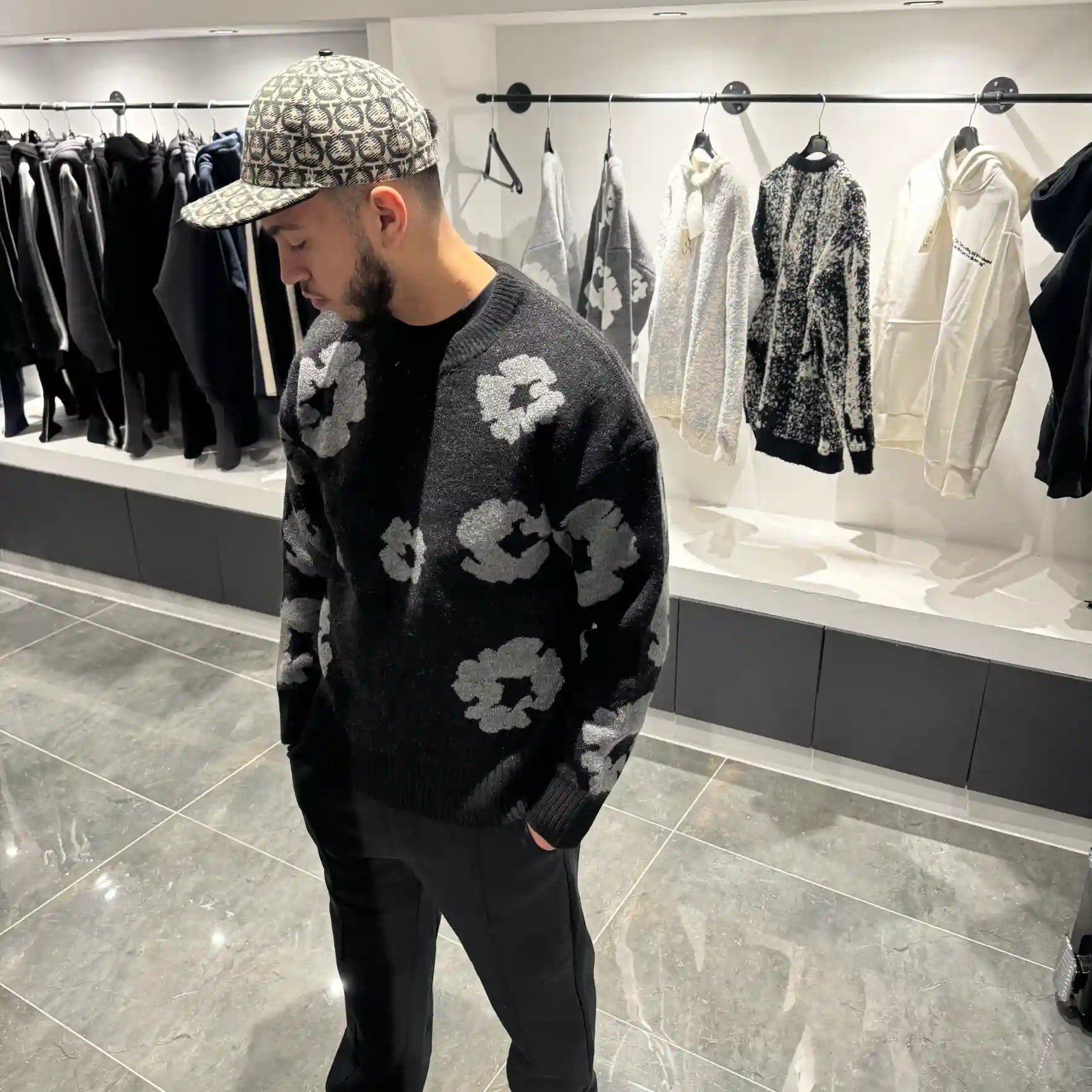 Silhouette complète présentant le pull noir et ses motifs floraux gris répartis sur l'ensemble de la maille.