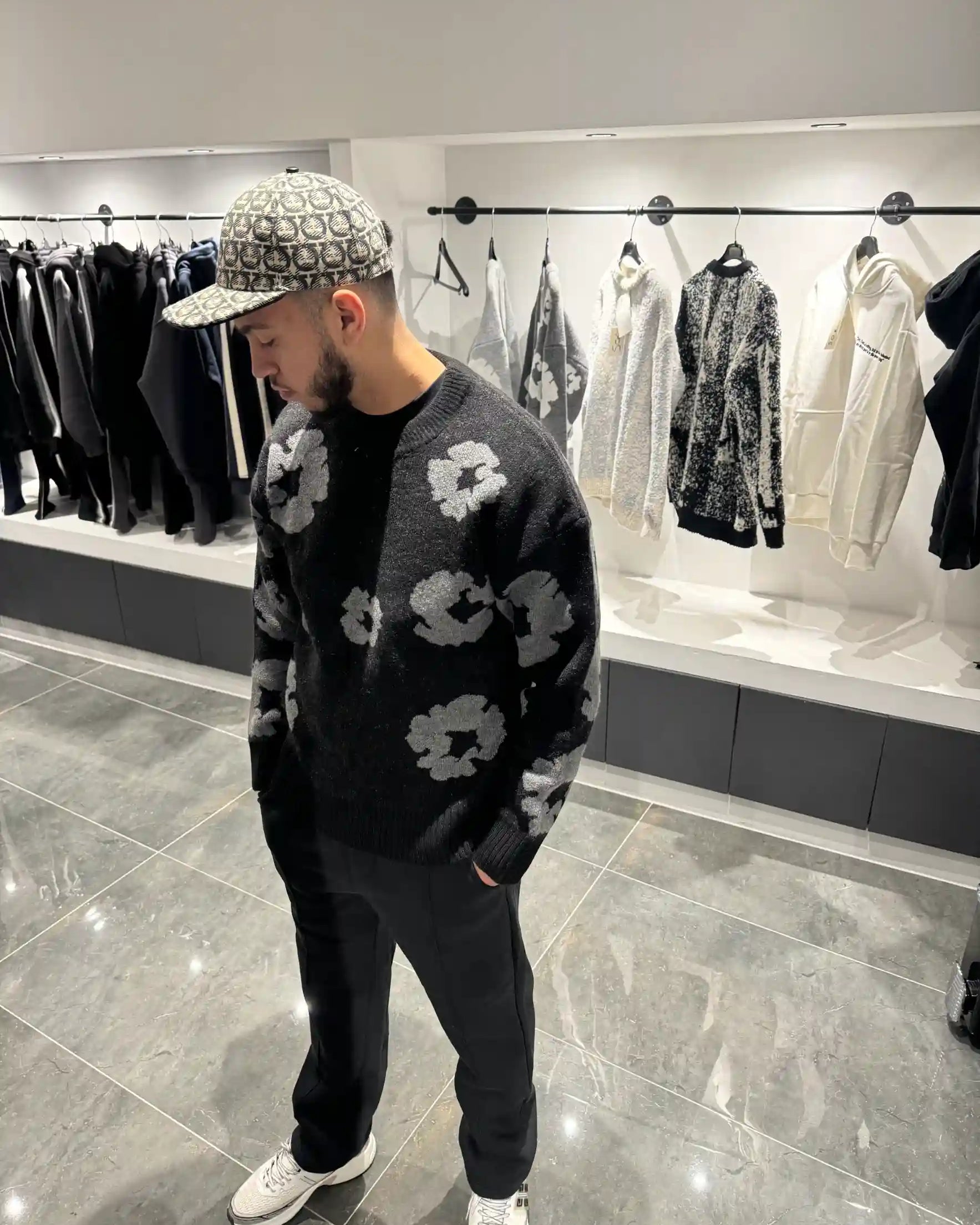 Silhouette complète présentant le pull noir et ses motifs floraux gris répartis sur l'ensemble de la maille.