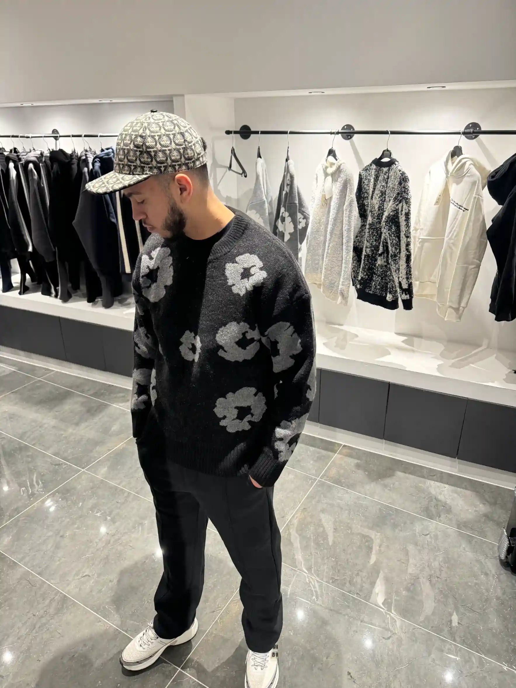 Silhouette complète présentant le pull noir et ses motifs floraux gris répartis sur l'ensemble de la maille.