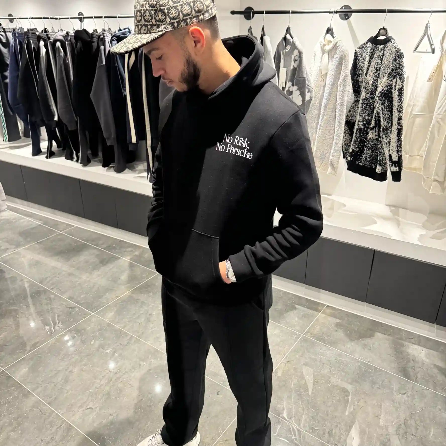 Vue de face montrant la coupe du hoodie noir, la poche kangourou et le texte blanc discret sur la poitrine.