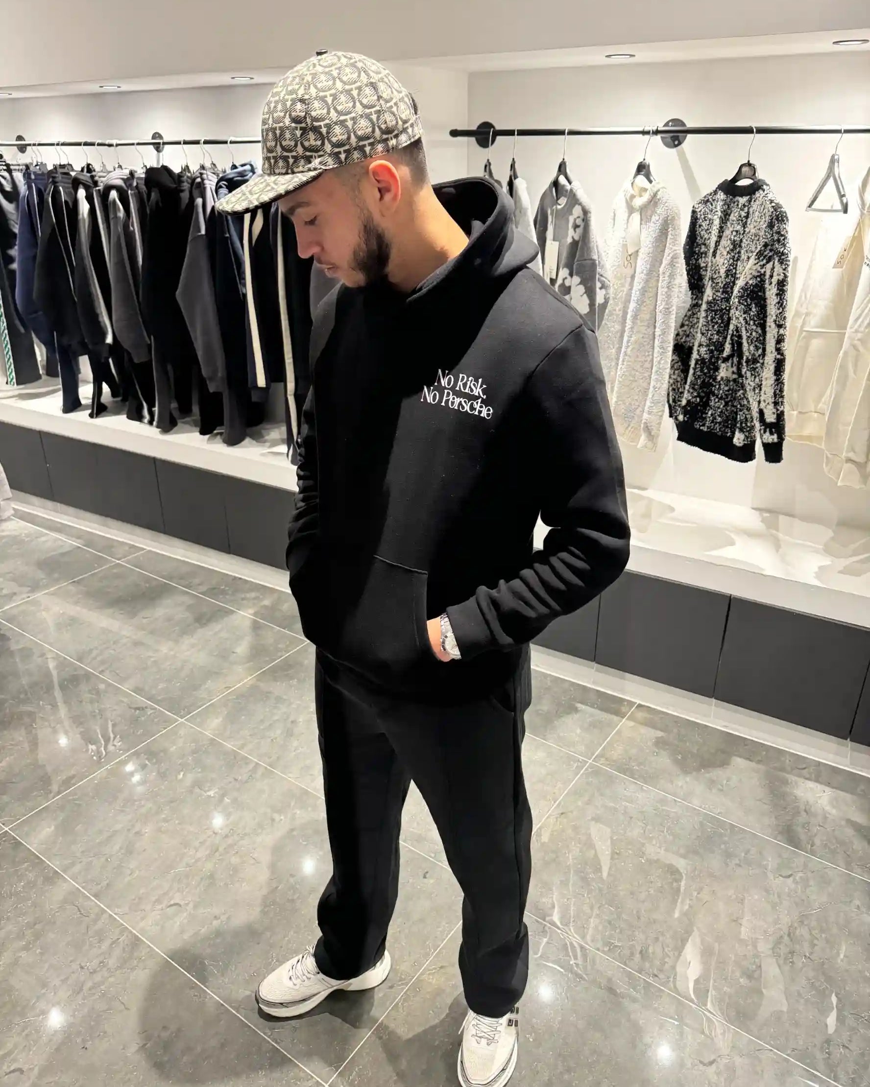 Vue de face montrant la coupe du hoodie noir, la poche kangourou et le texte blanc discret sur la poitrine.