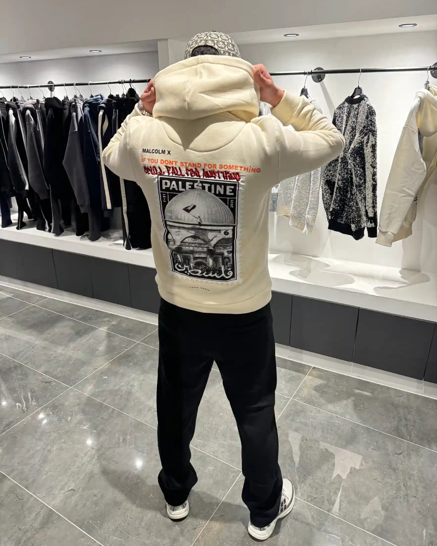 Silhouette complète de dos présentant le hoodie beige oversize et l'impact visuel de la grande photo.