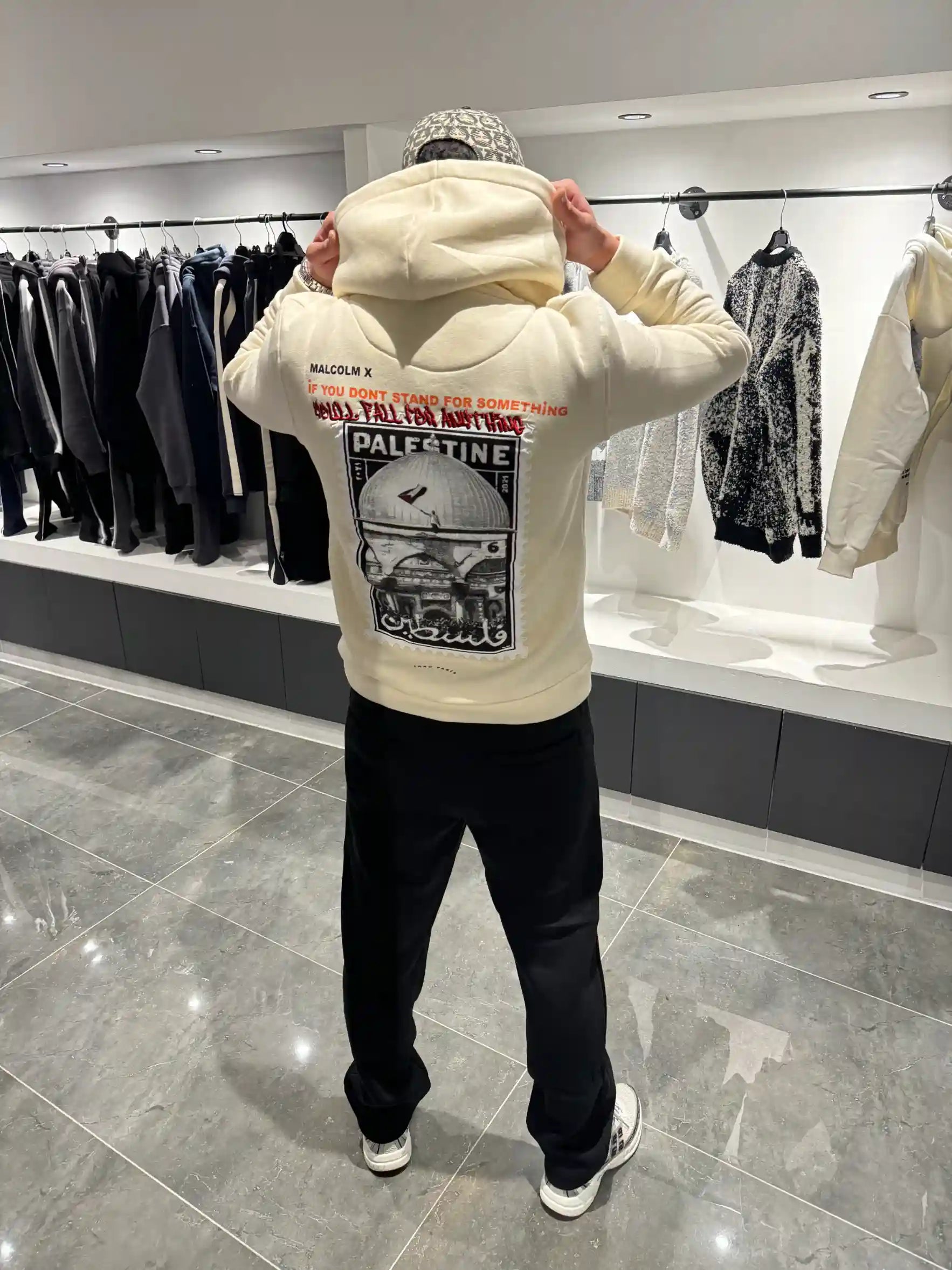 Silhouette complète de dos présentant le hoodie beige oversize et l'impact visuel de la grande photo.