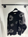 Présentation du pull noir sur cintre, illustrant le tombé fluide et la répartition des motifs floraux.