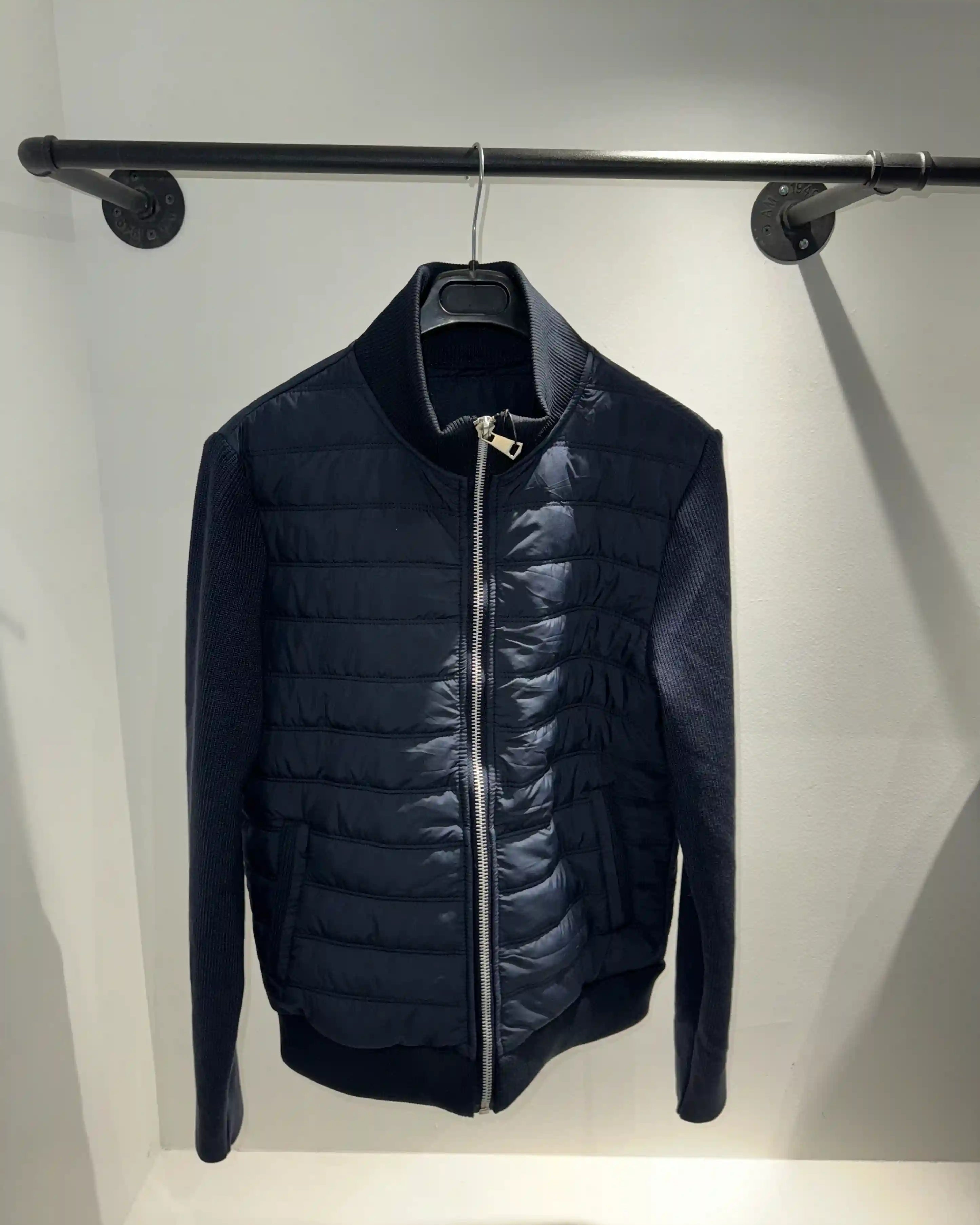 Présentation de la veste hybride bleu foncé sur cintre, illustrant le tombé impeccable et le mariage des matières.