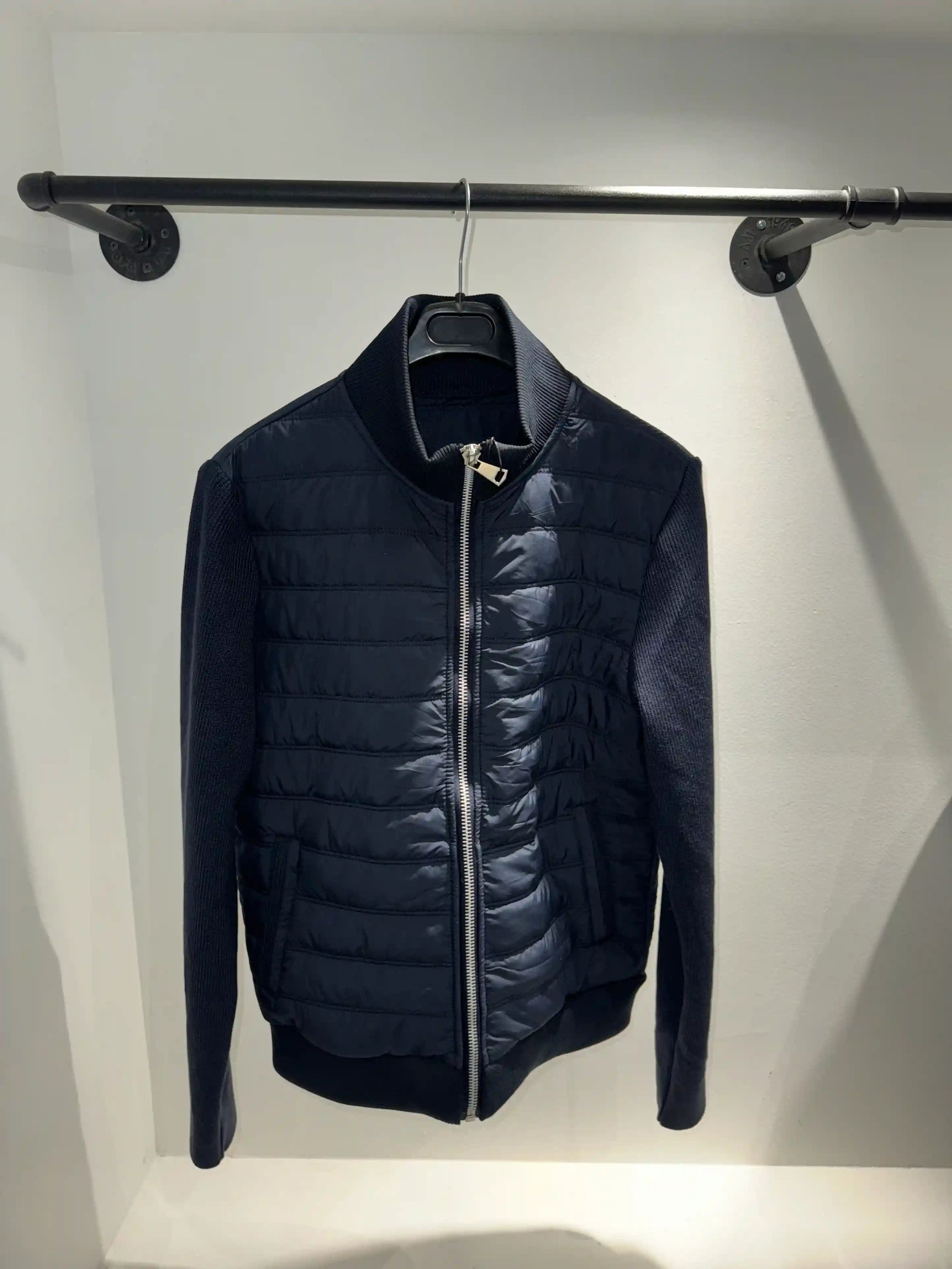Présentation de la veste hybride bleu foncé sur cintre, illustrant le tombé impeccable et le mariage des matières.