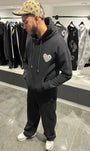 Hoodie noir premium présentant le logo cœur gris en matière éponge brodé en relief sur la poitrine.