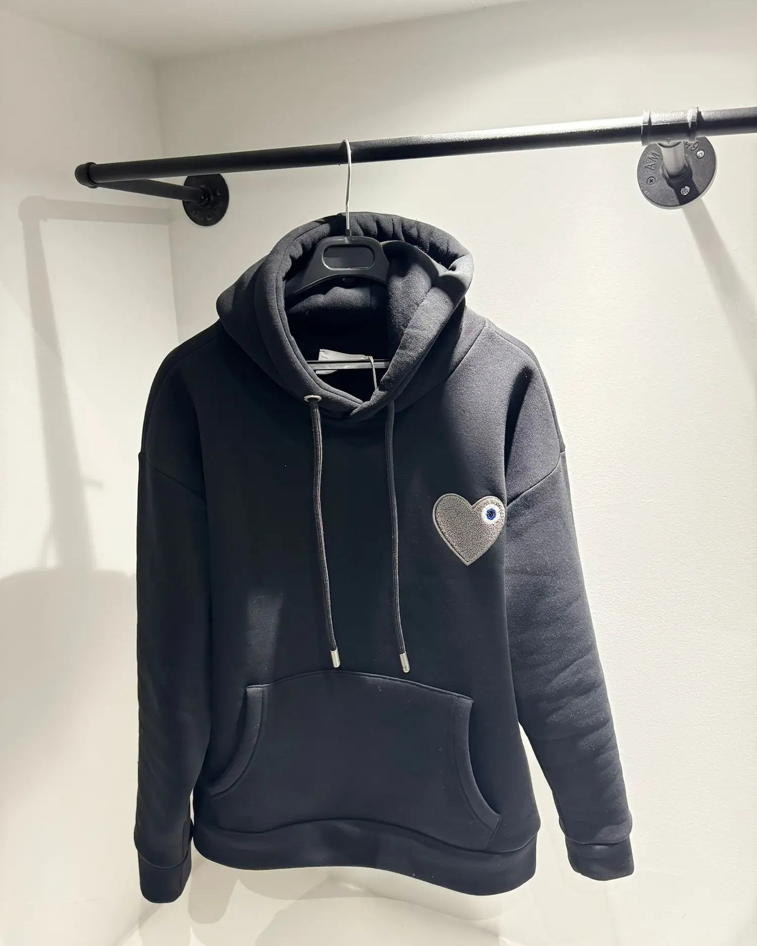 Gros plan sur le contraste de texture entre le coton noir lisse et le cœur gris brodé en bouclette.