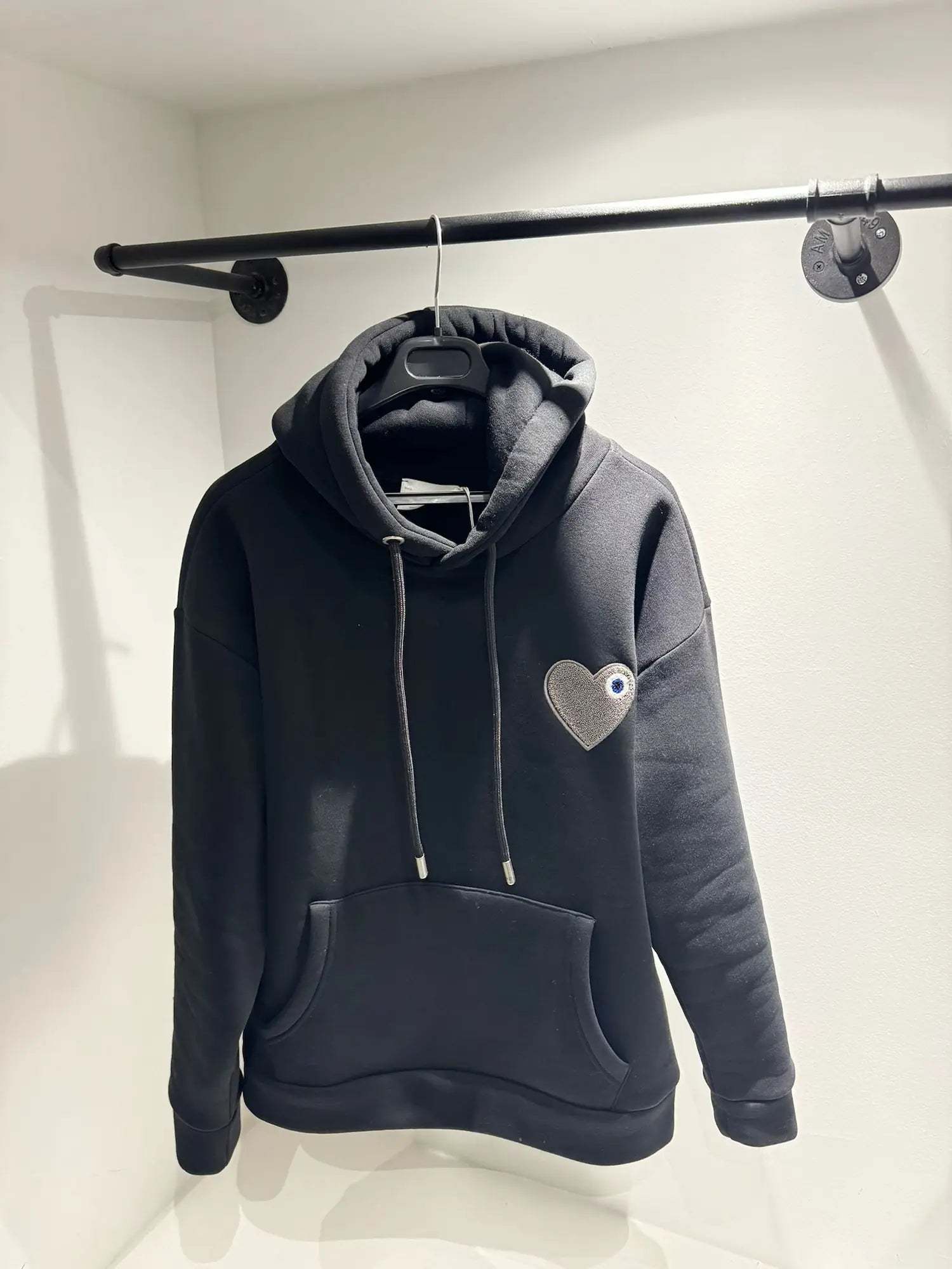 Gros plan sur le contraste de texture entre le coton noir lisse et le cœur gris brodé en bouclette.
